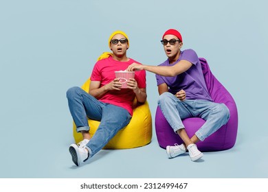 Full body shocked amazed young couple two friends men wear casual clothes in 3d glasses watch movie film hold bucket of popcorn in cinema sit in bag chair isolated on yellow background studio portrait - Powered by Shutterstock