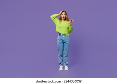 Full body shocked confused sad young woman she wearing casual green knitted sweater hold head use mobile cell phone isolated on plain pastel purple background studio portrait. People lifestyle concept - Shutterstock ID 2244386039