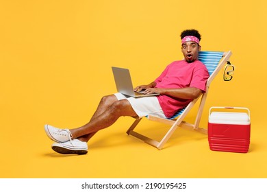 Full Body Shocked Surprised Fun Young Man 20s He Wearing Pink T-shirt Bandana Near Hotel Pool Hold Use Work On Laptop Pc Computer Isolated On Plain Yellow Background. Summer Vacation Sea Rest Concept