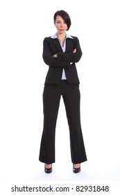 Full Body Shot Of Beautiful Young Confident Business Woman, Standing With Arms Folded And Serious Expression. Woman Is Wearing A Black Business Suit And High Heels.
