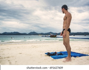 Full Body Shot Of A Handsome Young Man Standing On A Beach In Phuket Island, Thailand, Shirtless Wearing Boxer Shorts, Showing Muscular Fit Body