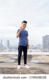 Full Body Shot Of Happy Young Handsome Multi Ethnic Man Giving Ok Sign Against View Of The City