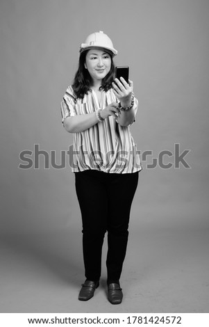 Full body shot of mature beautiful Asian businesswoman as engineer with phone