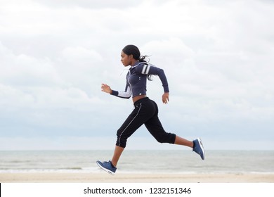 Full Body Side Portrait Of African American Woman Running By The Beach