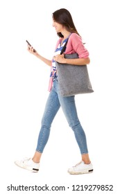 Full Body Side Portrait Of Fashionable Young Asian Woman Walking With Purse And Mobile Phone Against Isolated White Background