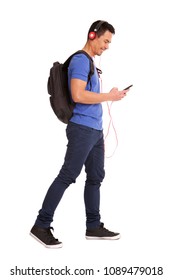 Full Body Side Portrait Of Happy Mature Man Holding Cellphone With Backpack And Headphones On White Background