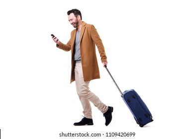 Full Body Side Portrait Of Happy Man Walking With Mobile Phone And Suitcase Against Isolated White Background