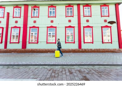 Full Body Side Portrait Of Happy Travel Man With Suitcase Walking Along The Building In City.