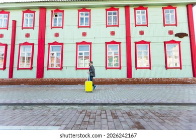 Full Body Side Portrait Of Happy Travel Man With Suitcase Walking Along The Building In City.