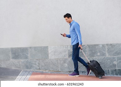 Full Body Side Portrait Of Happy Travel Man Walking With Cellphone And Bag