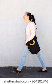 Full Body Side Portrait Of Happy Asian Woman Walking With Bag