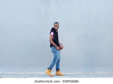 Full Body Side Portrait Of A Smiling African American Man Walking With Basketball