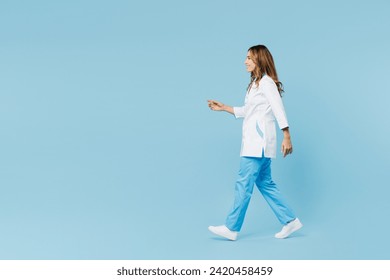 Full body side profile view smiling female doctor woman she wears white medical gown suit work in hospital clinic office walk go isolated on plain blue background studio. Health care medicine concept - Powered by Shutterstock