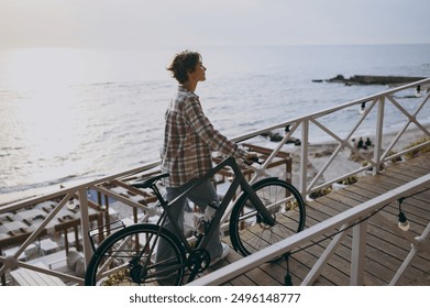 Full body side profile view happy young woman she wears shirt casual clothes walk stroll with bicycle rest near sea ocean sand shore beach outdoor seaside in summer day free time. Lifestyle concept - Powered by Shutterstock