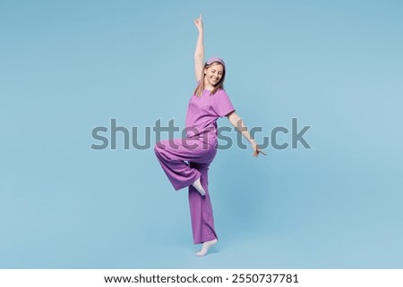 Full body side profile view calm happy cheerful young woman wear purple pyjamas jam sleep eye mask rest relax at home raise up hands isolated on plain blue cyan background. Good mood night nap concept