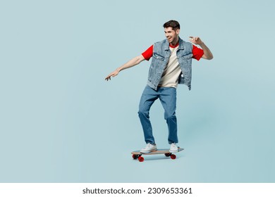 Full body side view active young man he wear denim vest red t-shirt casual clothes riding skateboard pennyboard isolated on plain pastel light blue cyan background studio portrait. Lifestyle concept - Powered by Shutterstock