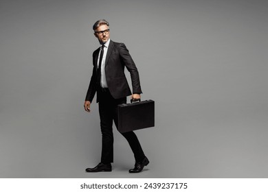 Full body side view adult employee business man corporate lawyer wears formal black suit shirt tie work in office hold in hand briefcase look aside isolated on plain grey background studio portrait - Powered by Shutterstock