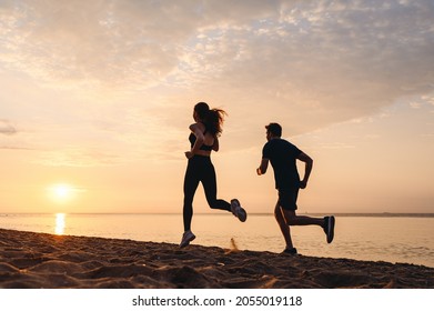 Full body side view couple young friends sporty sportsman sportswoman woman man in sport clothes warm up training running jog on seaside sunrise over sea sand ocean beach outdoor in summer day morning - Shutterstock ID 2055019118
