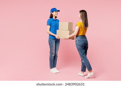 Full body side view delivery employee woman wear blue cap t-shirt uniform workwear work as dealer courier holding cardboard boxes give to receiver isolated on plain pink background. Service concept - Powered by Shutterstock