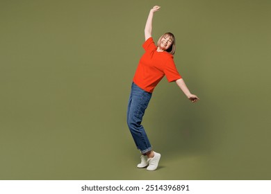 Full body side view elderly blonde woman 50s years old wear orange t-shirt casual clothes stand on toes with outstretched hands lean back isolated on plain pastel green background. Lifestyle concept - Powered by Shutterstock