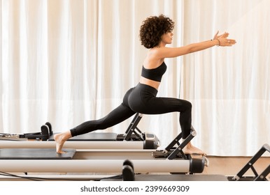 Full body side view of fit woman in sportswear doing exercise on pilates reformer during training in gym - Powered by Shutterstock