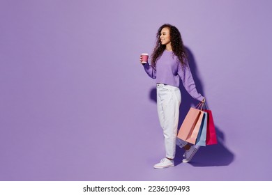 Full body side view fun young woman wear pullover hold in hand paper package bags after shopping cup coffee walk go isolated on plain pastel light purple background. Black Friday sale buy day concept - Shutterstock ID 2236109493