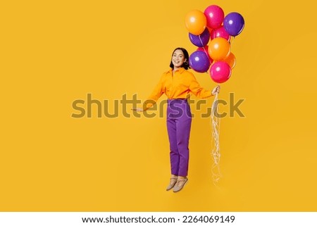 Full body side view fun happy young woman wearing casual clothes hat celebrating hold bunch of balloons jump pov flying in air isolated on plain yellow background. Birthday 8 14 holiday party concept