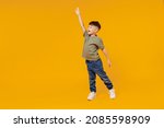 Full body side view little small smiling happy boy 6-7 years old wear green t-shirt walk go waving hand isolated on plain yellow background studio portrait. Mother