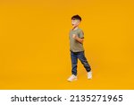 Full body side view little small smiling happy boy 6-7 years old wearing green t-shirt walk go strolling isolated on plain yellow background studio portrait. Mother