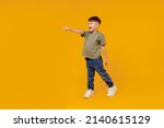 Full body side view little small smiling happy boy 6-7 years old wearing green t-shirt walk go point finger aside on area isolated on plain yellow background Mother