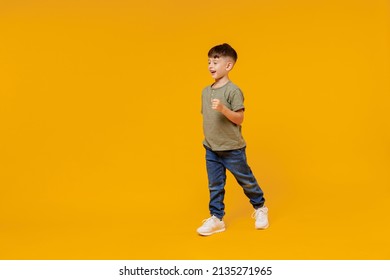 Full body side view little small smiling happy boy 6-7 years old wearing green t-shirt walk go strolling isolated on plain yellow background studio portrait. Mother's Day love family lifestyle concept - Shutterstock ID 2135271965