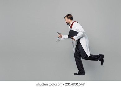 Full body side view male doctor man wears white medical gown suit work in hospital hold clipboard with paper documents run isolated on plain grey color background studio Healthcare medicine concept - Shutterstock ID 2314931549