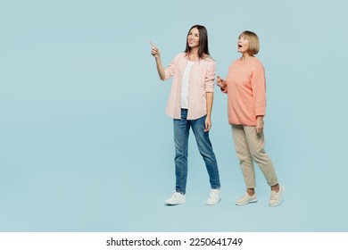 Full body side view smiling elder parent mom with young adult daughter two women together wearing casual clothes point index finger aside on area isolated on plain blue background. Family day concept - Shutterstock ID 2250641749