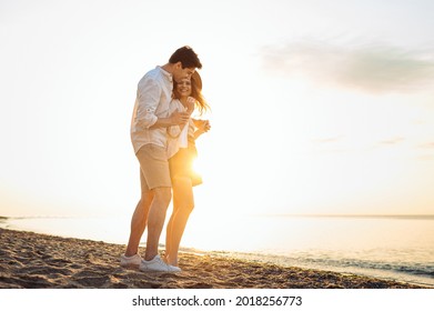 Full body side view sunlit smiling happy young couple two friends family man woman in casual clothes hug each other at sunrise over sea beach ocean outdoor exotic seaside in summer day sunset evening