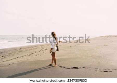 Full body side view of unrecognizable female traveler in casual clothes walking on sandy beach near sea against sky during sunset