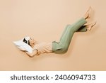Full body side view young calm Latin woman wears pyjamas jam sleep eye mask rest relax at home fly up hover over air fall down on pillow isolated on plain beige background. Good mood night nap concept