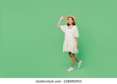 Full Body Side View Young Happy Smiling Fun Cheerful Woman She 20s Wear White Dress Hat Walking Go Waving Hand Isolated On Plain Pastel Light Green Background Studio Portrait. People Lifestyle Concept