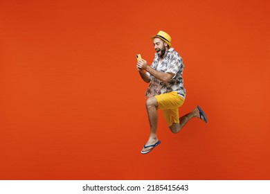 Full body side view young tourist man wear beach shirt hat jump high run fast use hold mobile cell phone isolated on plain orange background studio portrait. Summer vacation sea rest sun tan concept - Powered by Shutterstock