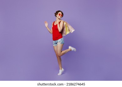 Full Body Side View Young Smiling Woman 20s She Wear Red Tank Shirt Eyeglasses Holding Package Bag With Purchases After Shopping Look Aside On Workspace Area Isolated On Plain Purple Background Studio