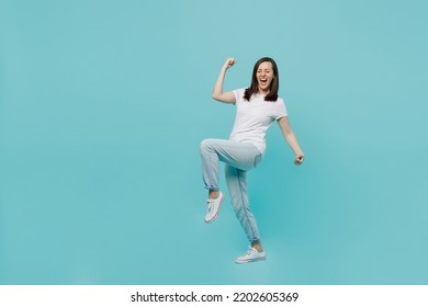 Full body side view young woman 20s she wear white t-shirt doing winner gesture celebrate clenching fists say yes isolated on plain pastel light blue cyan background studio. People lifestyle concept - Shutterstock ID 2202605369