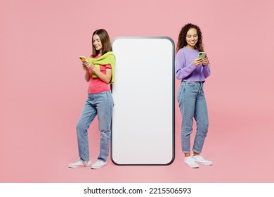 Full Body Side View Young Two Friends Women Wears Green Purple Shirts Near Big Huge Blank Screen Mobile Cell Phone With Copy Space Area Use Smartphone Isolated On Pastel Plain Pink Color Background