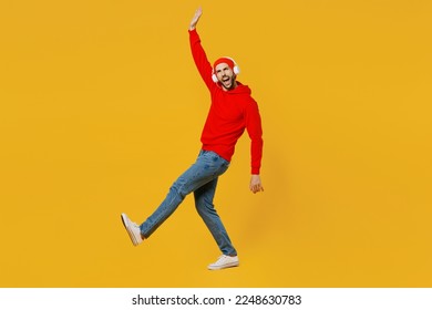 Full body side view young fun caucasian man wear red hoody headphones listen to music hat look camera raise up hand isolated on plain yellow color background studio portrait. People lifestyle concept - Powered by Shutterstock