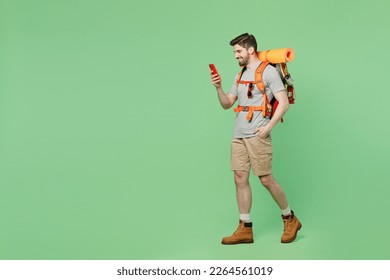 Full body side view young traveler white man carry backpack stuff mat walk use mobile cell phone isolated on plain green background. Tourist leads active lifestyle Hiking trek rest travel trip concept - Shutterstock ID 2264561019