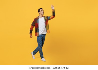 Full body side view young smiling happy middle eastern man 20s wear casual shirt white t-shirt walking going strolling waving hand isolated on plain yellow background studio People lifestyle concept - Shutterstock ID 2266577643