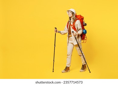 Full body side view young woman carry bag with stuff mat hold trekking poles isolated on plain yellow background. Tourist leads active lifestyle walk on spare time Hiking trek rest travel trip concept - Shutterstock ID 2357714573