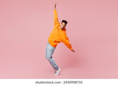 Full body side view young man of African American ethnicity wear yellow hoody casual clothes stand on toes with outstretched hands dance lean back isolated on plain pink background. Lifestyle concept - Powered by Shutterstock