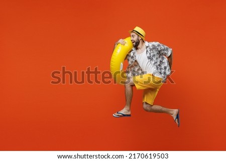 Full body side view young happy tourist man wear beach shirt hat hold inflatable ring jump high run fast isolated on plain orange background studio portrait. Summer vacation sea rest sun tan concept