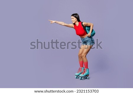 Full body side view young latin woman wear red casual clothes rollers backpack rollerblading point index finger aside on area isolated on plain pastel purple background. Summer sport leisure concept