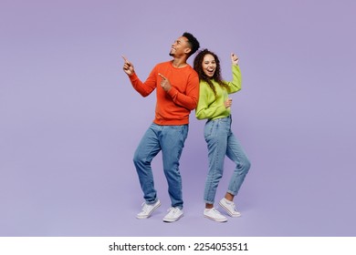 Full body sideways fun young couple two friends family man woman of African American ethnicity wear casual clothes together point finger aside on area isolated on pastel plain light purple background - Powered by Shutterstock