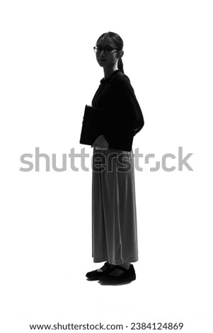 Full body silhouette of a young Asian woman standing seriously.